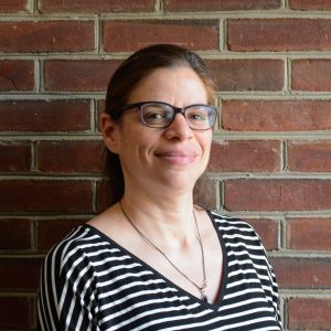 Headshot of Dr. Ariel Bierbaum standing in front of a red brick wall.