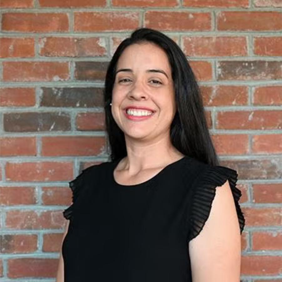 Headshot of Priscila B R Alves smiling in front of a brick wall